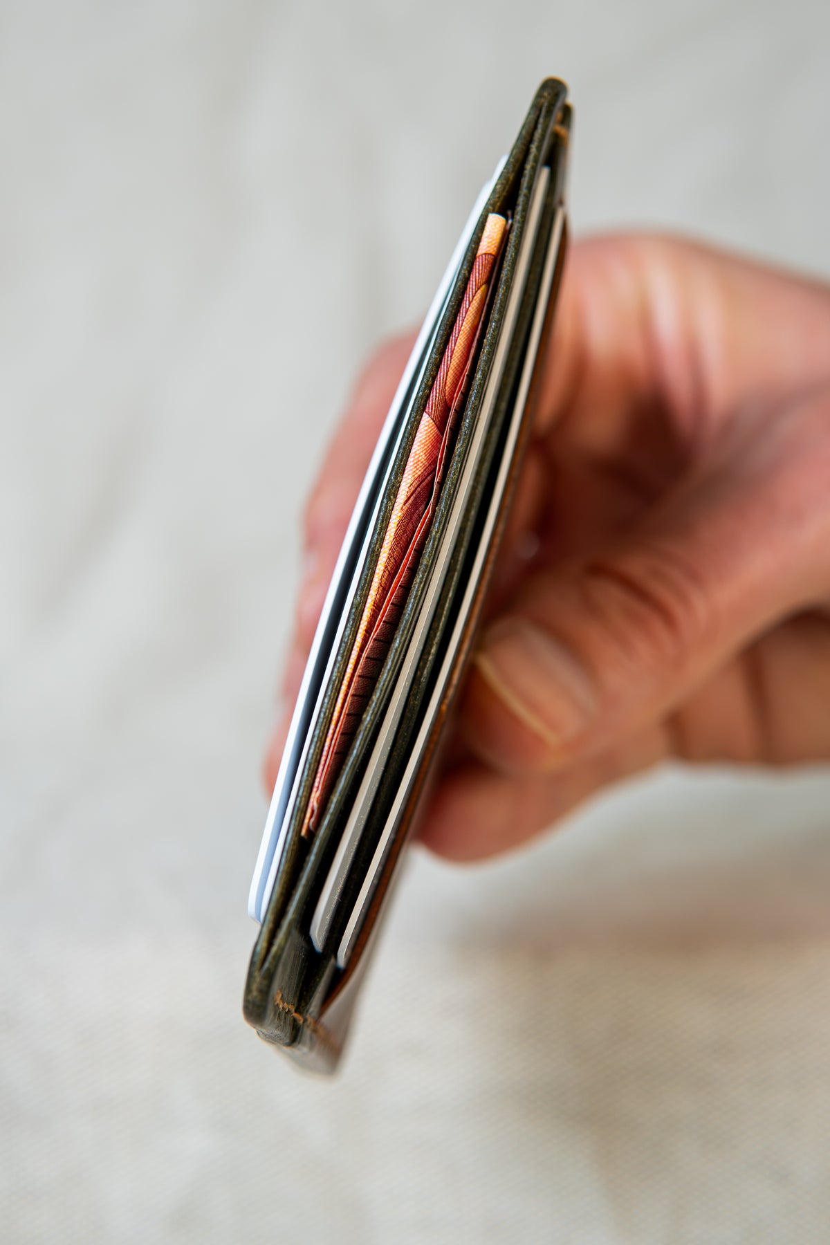 Porte-cartes Hautacam en cuir cognac et olive, tenu en main avec cartes et billet