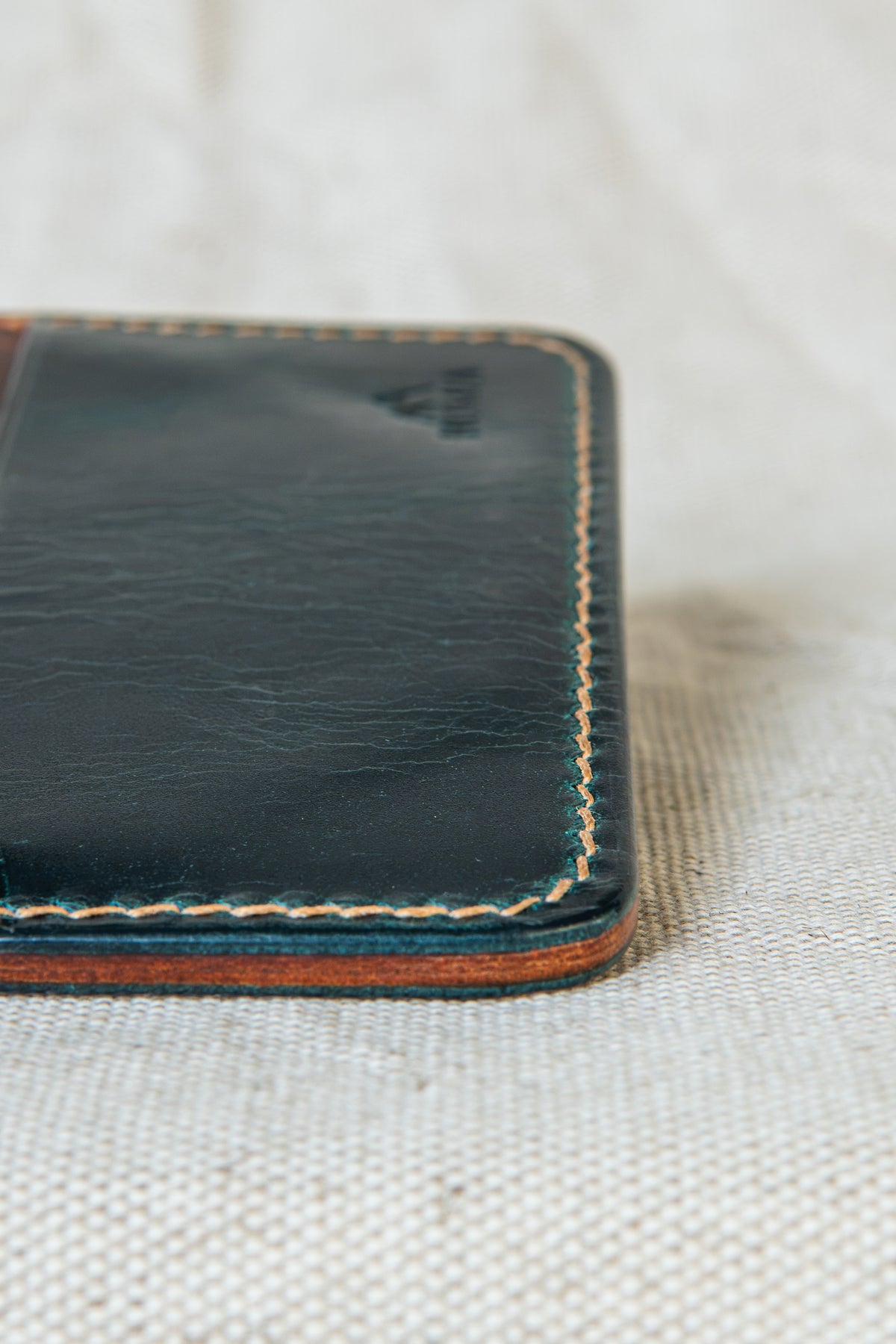 Détail de la couture main au point sellier du porte-cartes Hautacam en cuir turquoise et cognac
