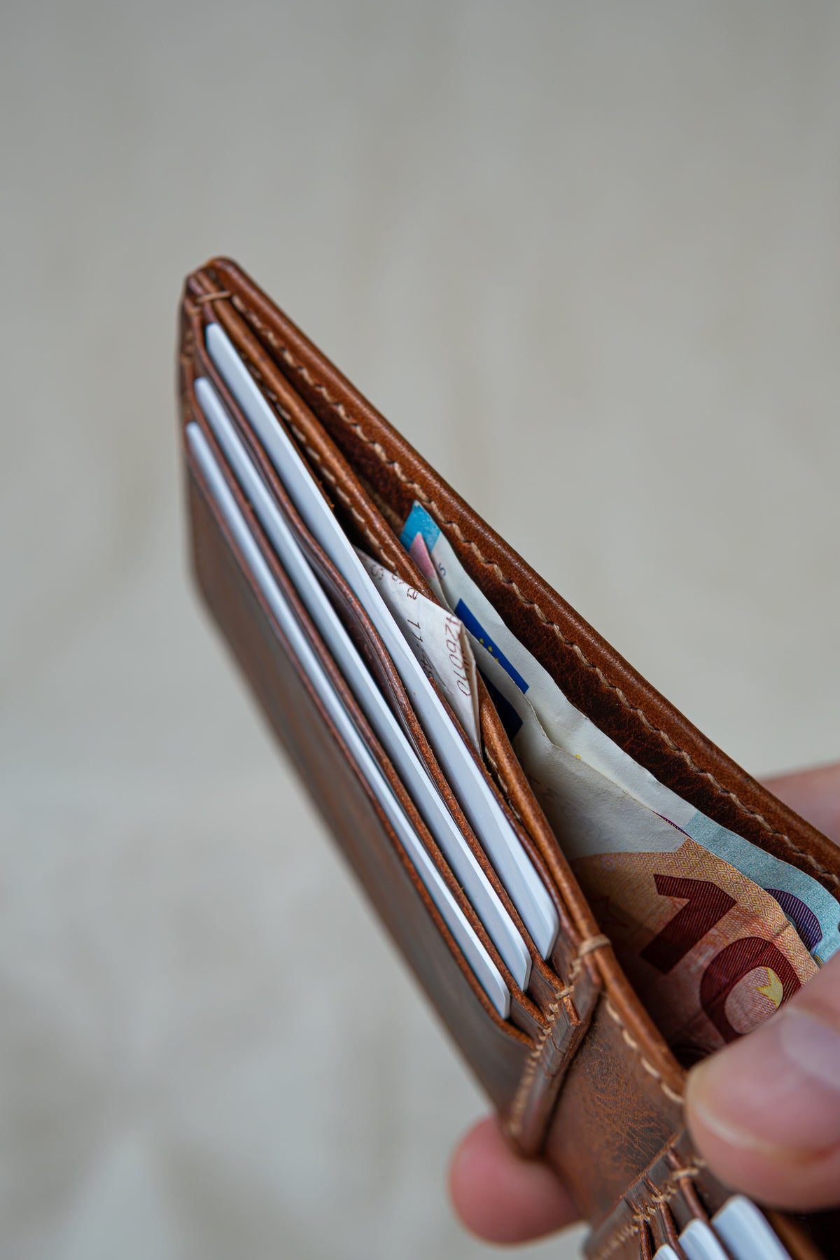 Portefeuille Tourmalet en cuir cognac, tenu en main ouvert avec cartes et billets