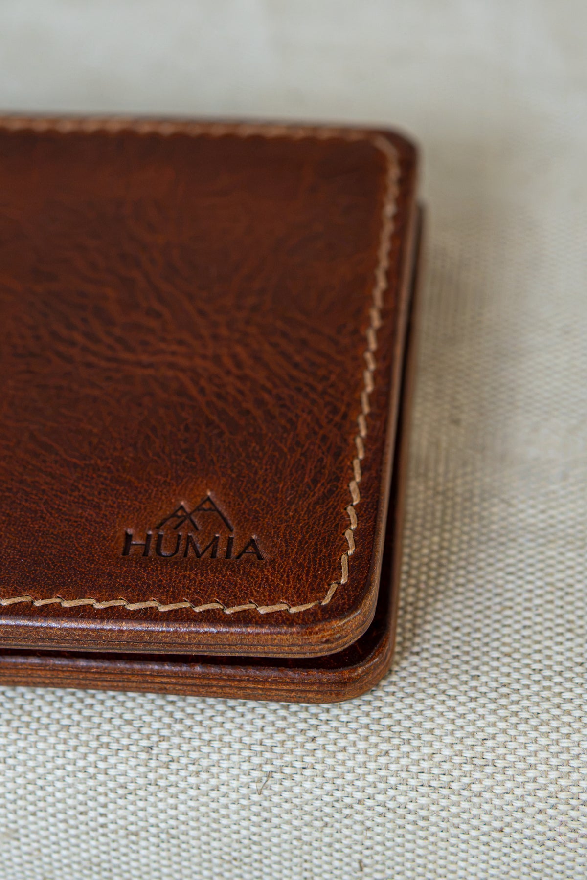 Portefeuille Tourmalet en cuir cognac, détails sur le logo et la couture main au point sellier