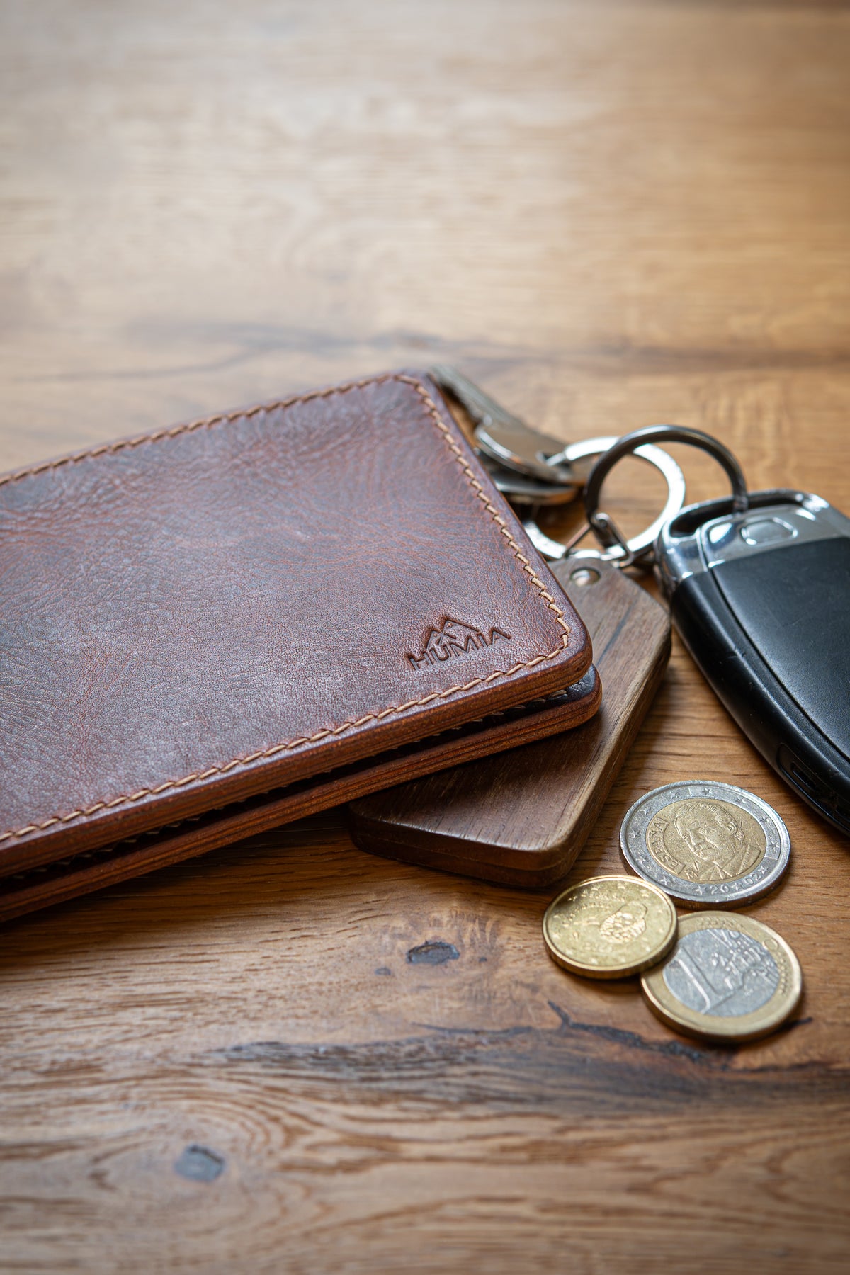 Portefeuille Tourmalet en cuir cognac, posé sur table bois avec clé et pièces monnaie