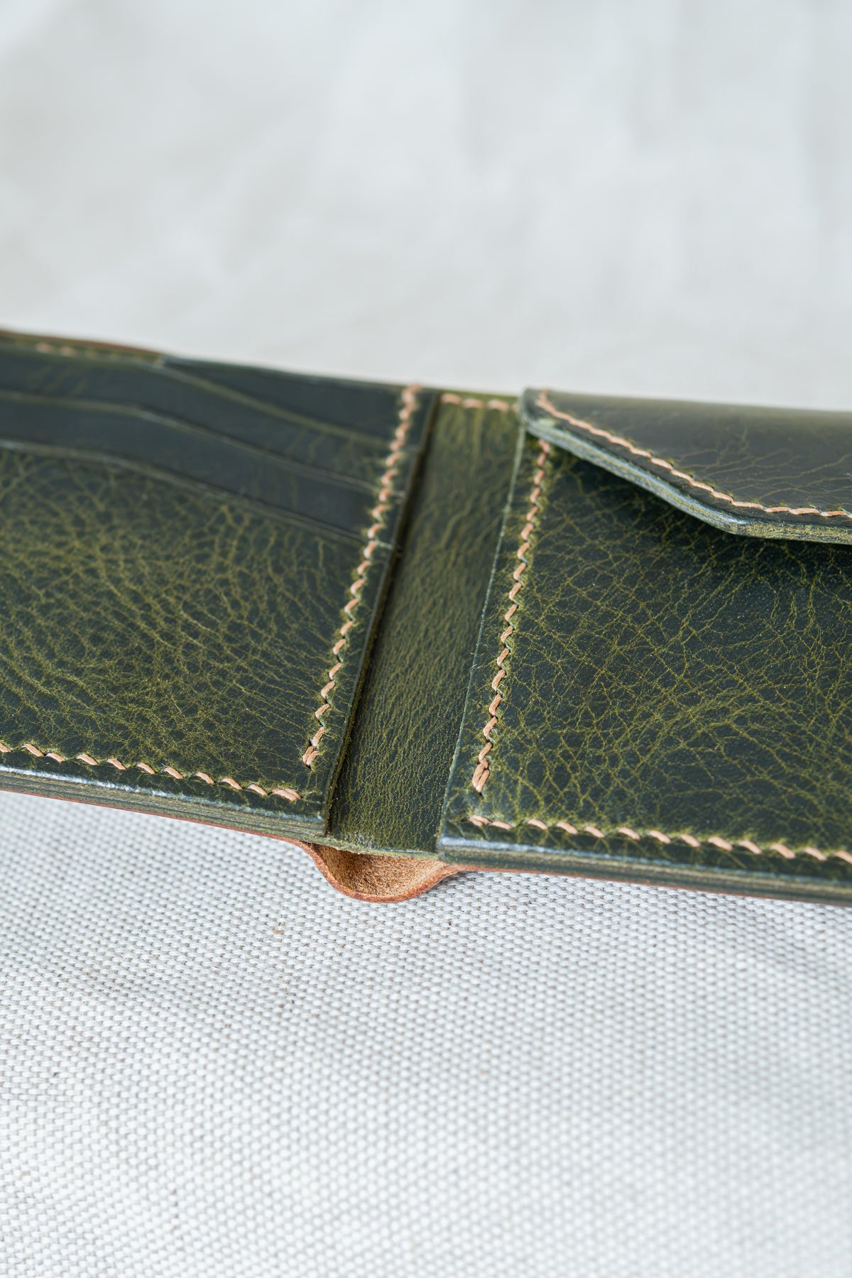 Portefeuille Vignemale en cuir cognac et olive, ouvert, détails sur la couture main au point sellier