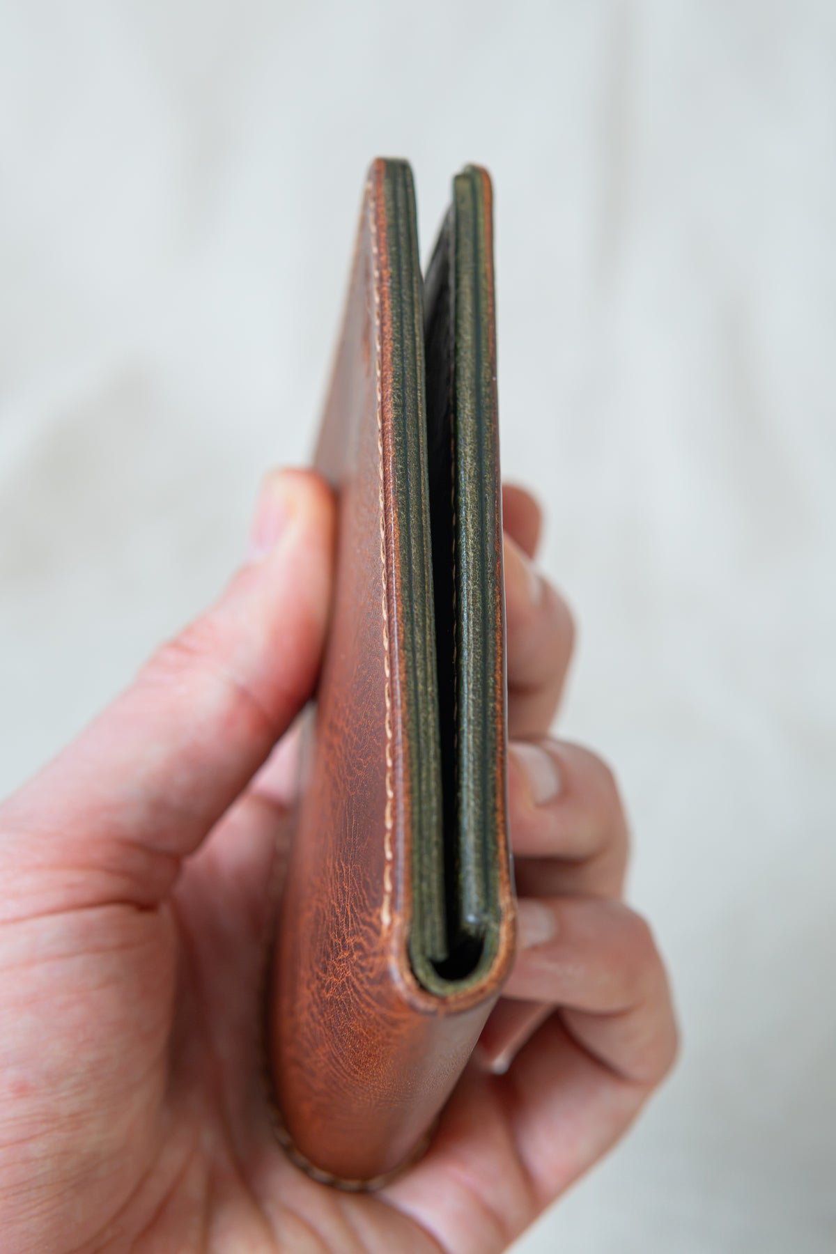 Portefeuille Vignemale en cuir cognac et olive, tenu en main fermé