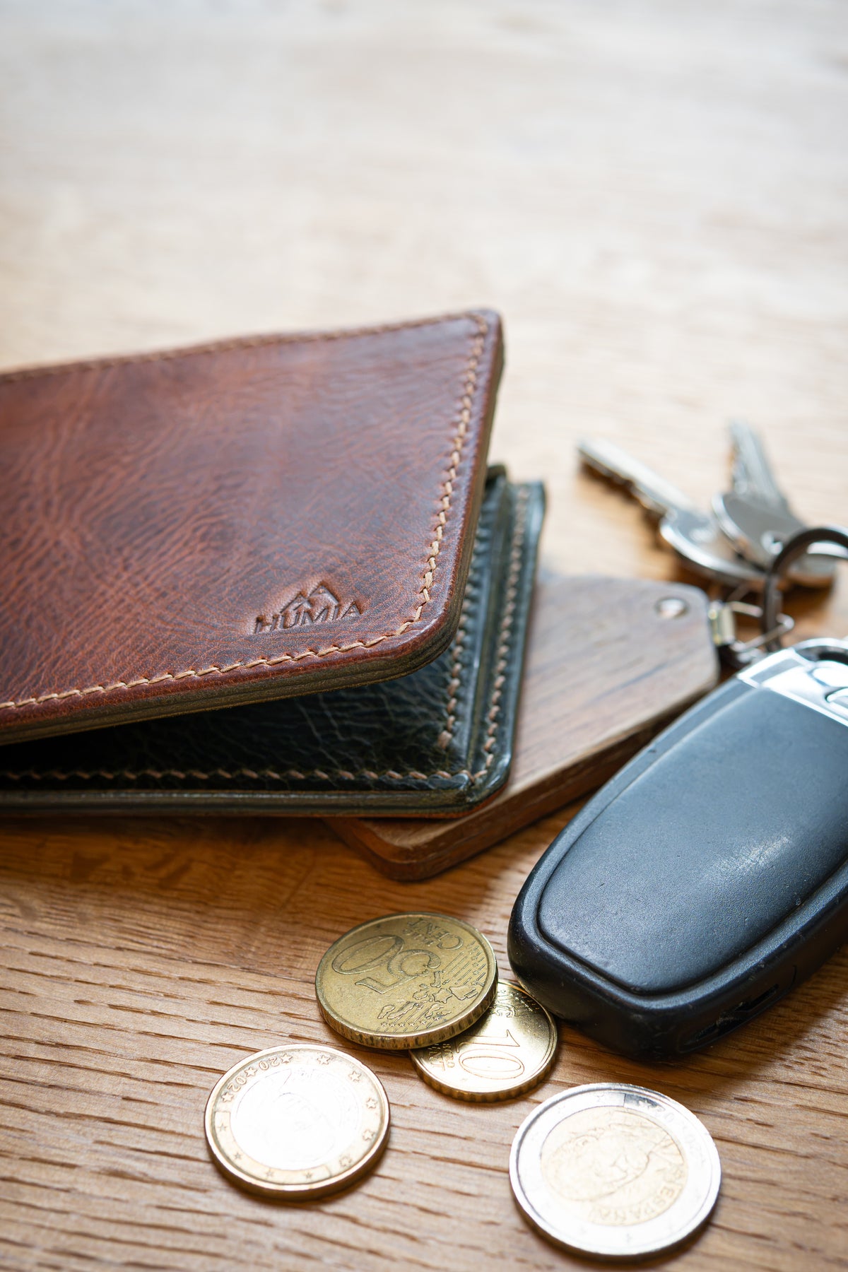 Portefeuille Vignemale en cuir cognac et olive, posé sur table bois avec clés et pièces monnaie