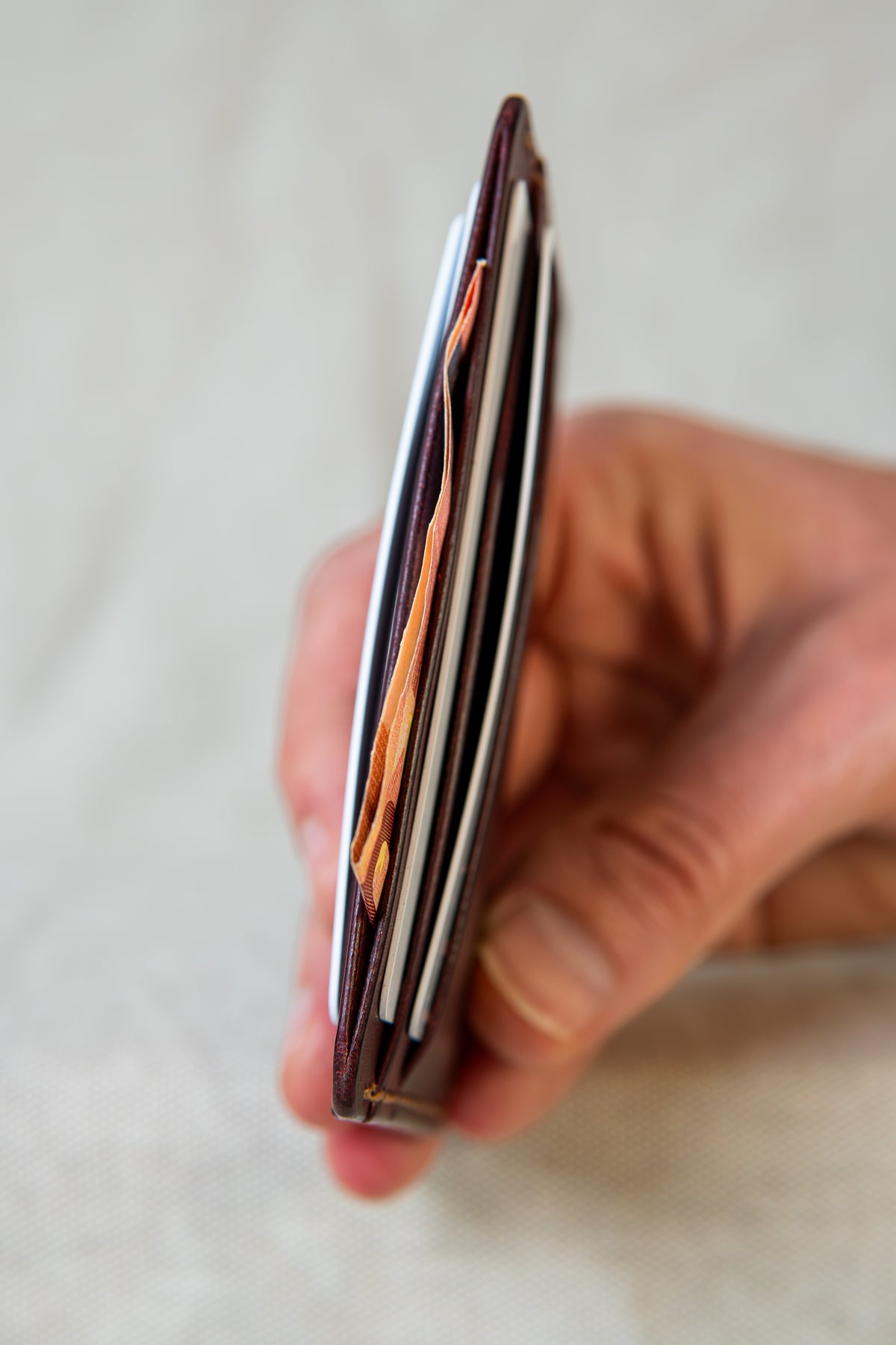 Porte-cartes Hautacam en cuir bordeaux et bourgogne, tenu dans la main avec cartes et billets