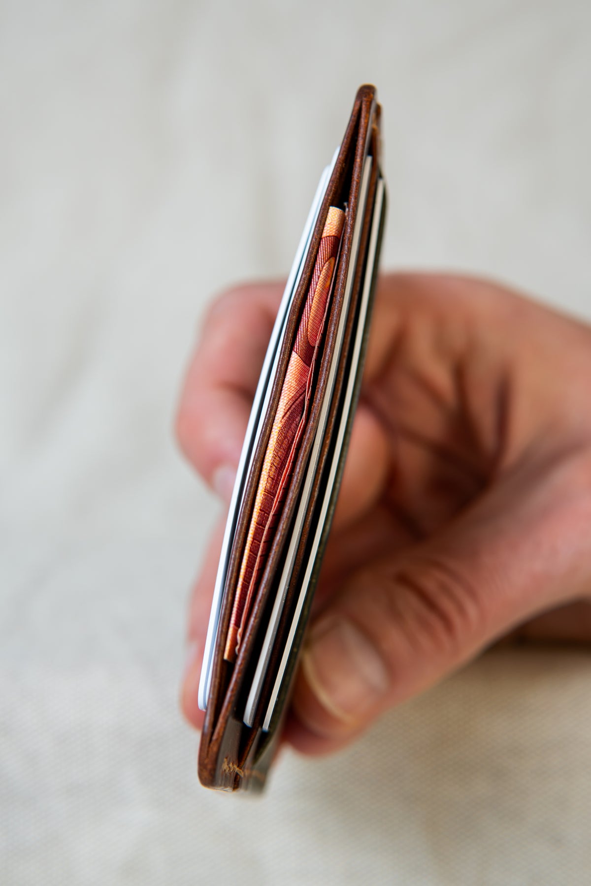 Porte-cartes Hautacam en cuir olive et cognac, tenu en main avec cartes et billets