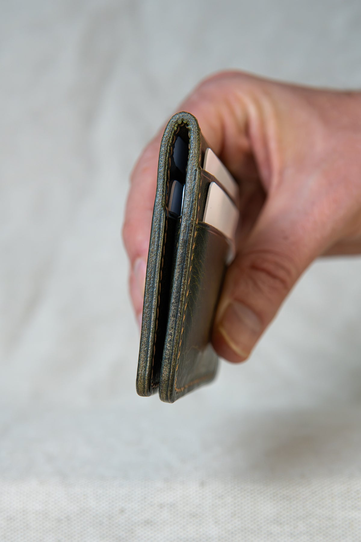 Porte-cartes Soulor en cuir olive, tenu en main avec cartes