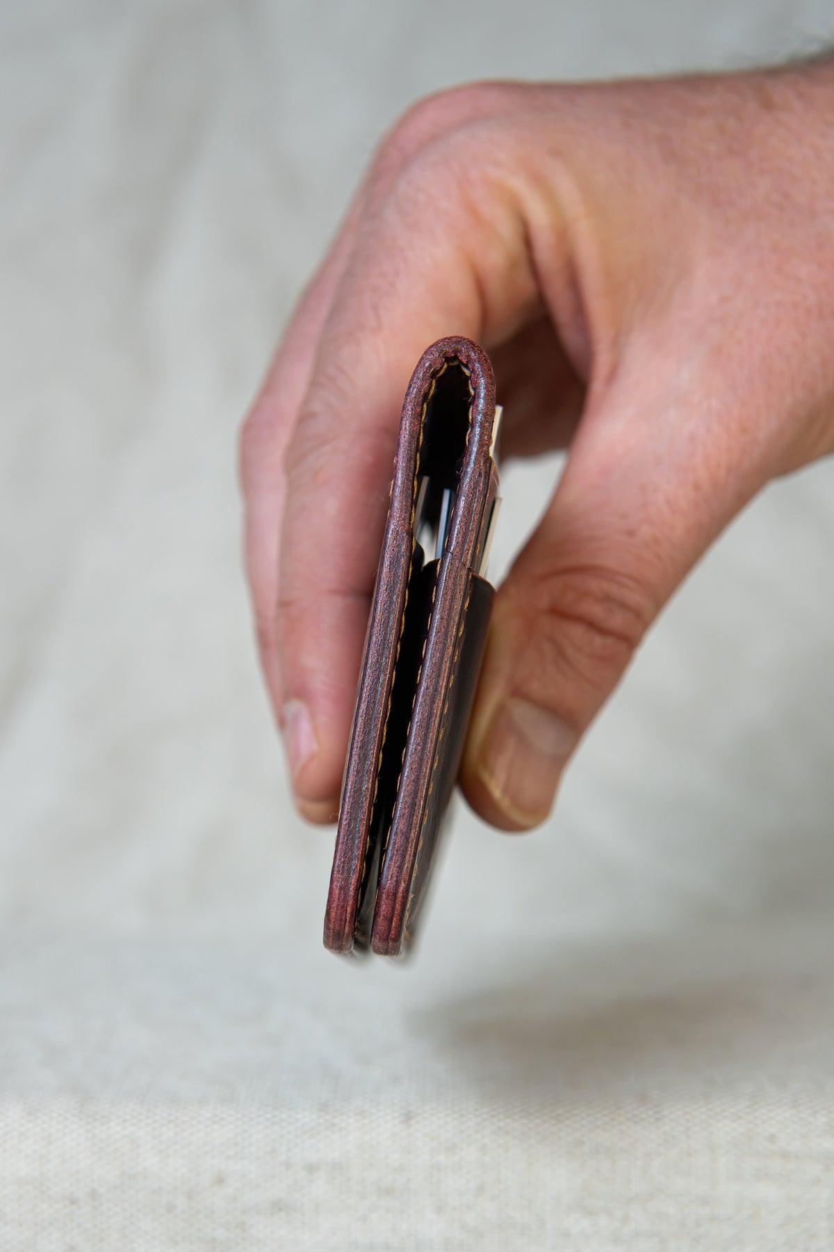 Porte-cartes Soulor en cuir bordeaux, tenu en main vue de la tranche avec cartes