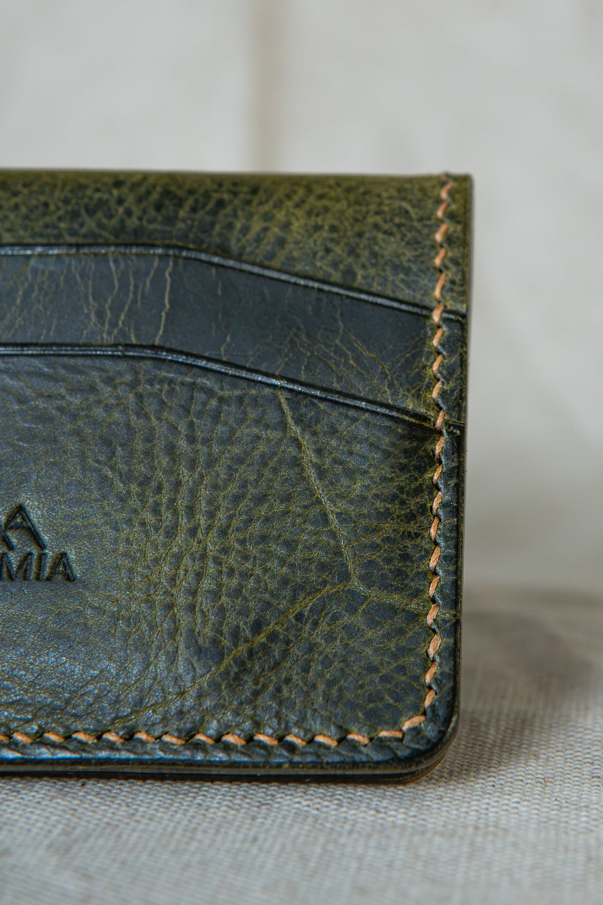 Détail de la couture main au point sellier du porte-cartes Soulor en cuir olive