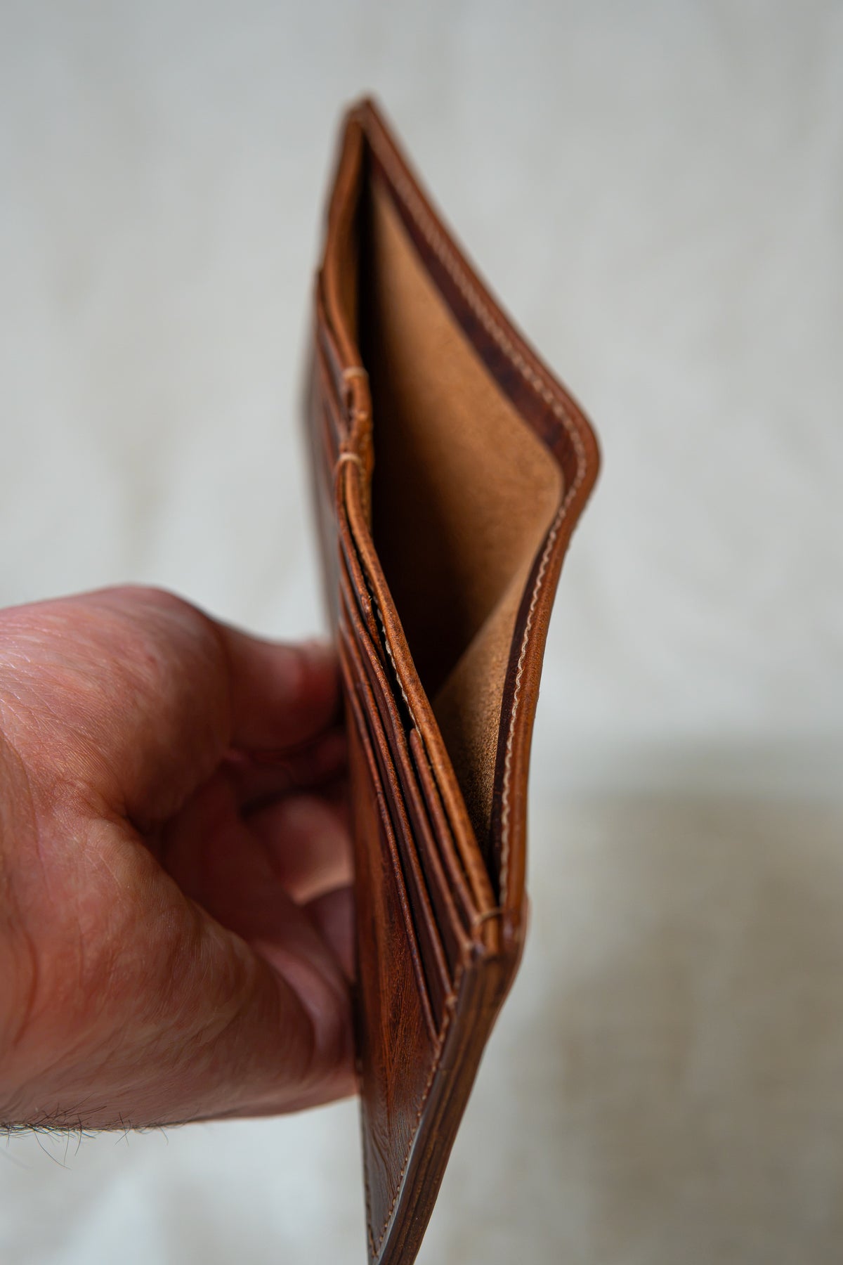 Portefeuille Tourmalet en cuir cognac, tenu en main ouvert