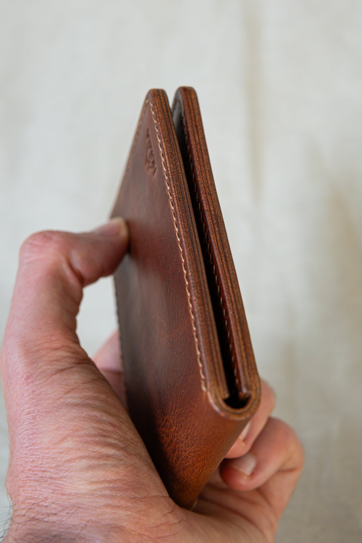 Portefeuille Tourmalet en cuir cognac, tenu en main fermé