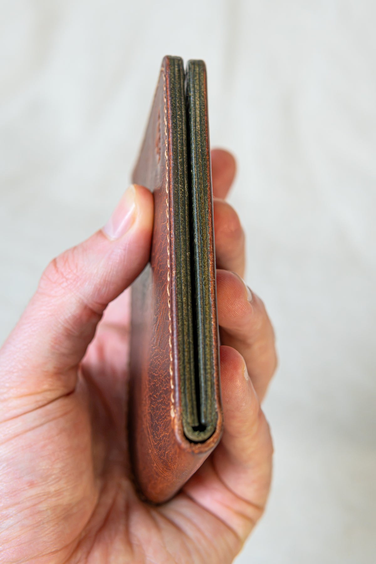 Portefeuille Tourmalet en cuir cognac et olive, fermé en main