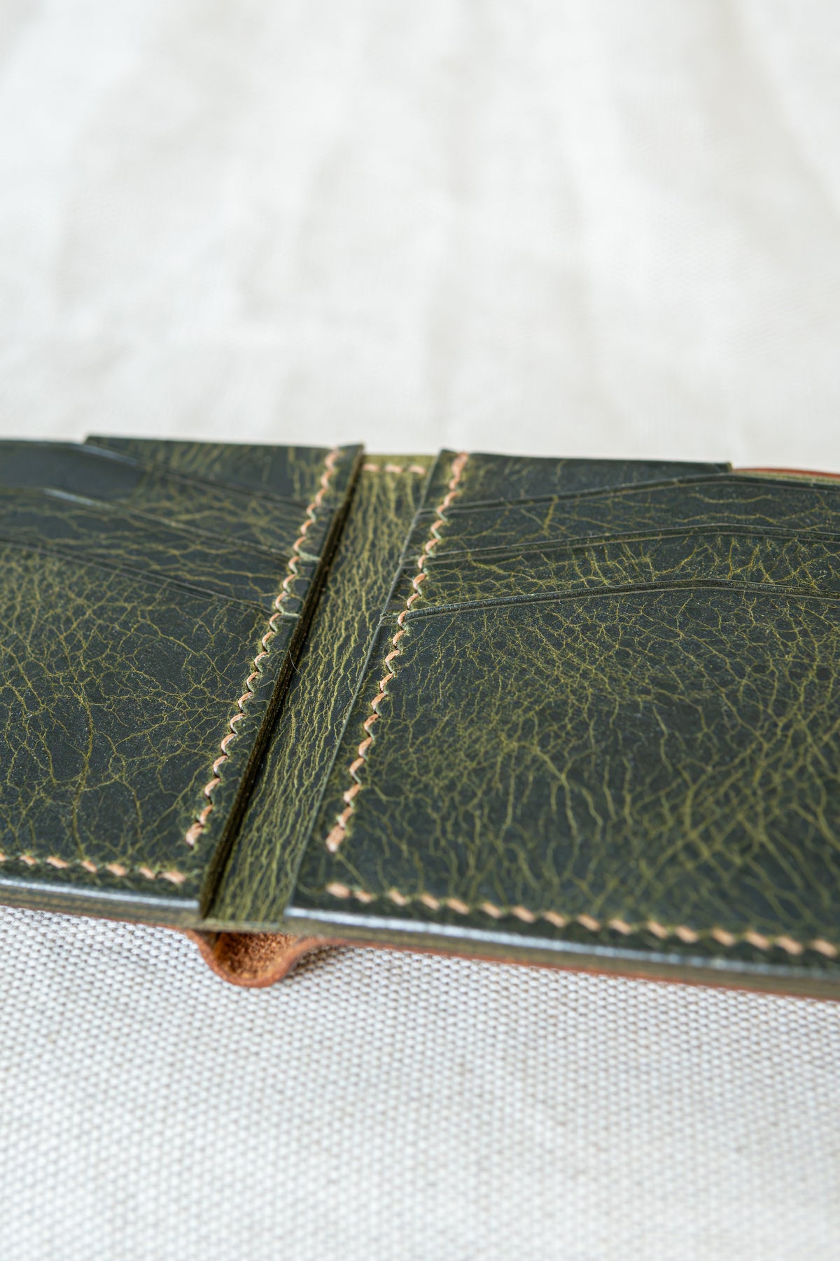 Portefeuille Tourmalet en cuir cognac et olive, ouvert avec détails sur les coutures