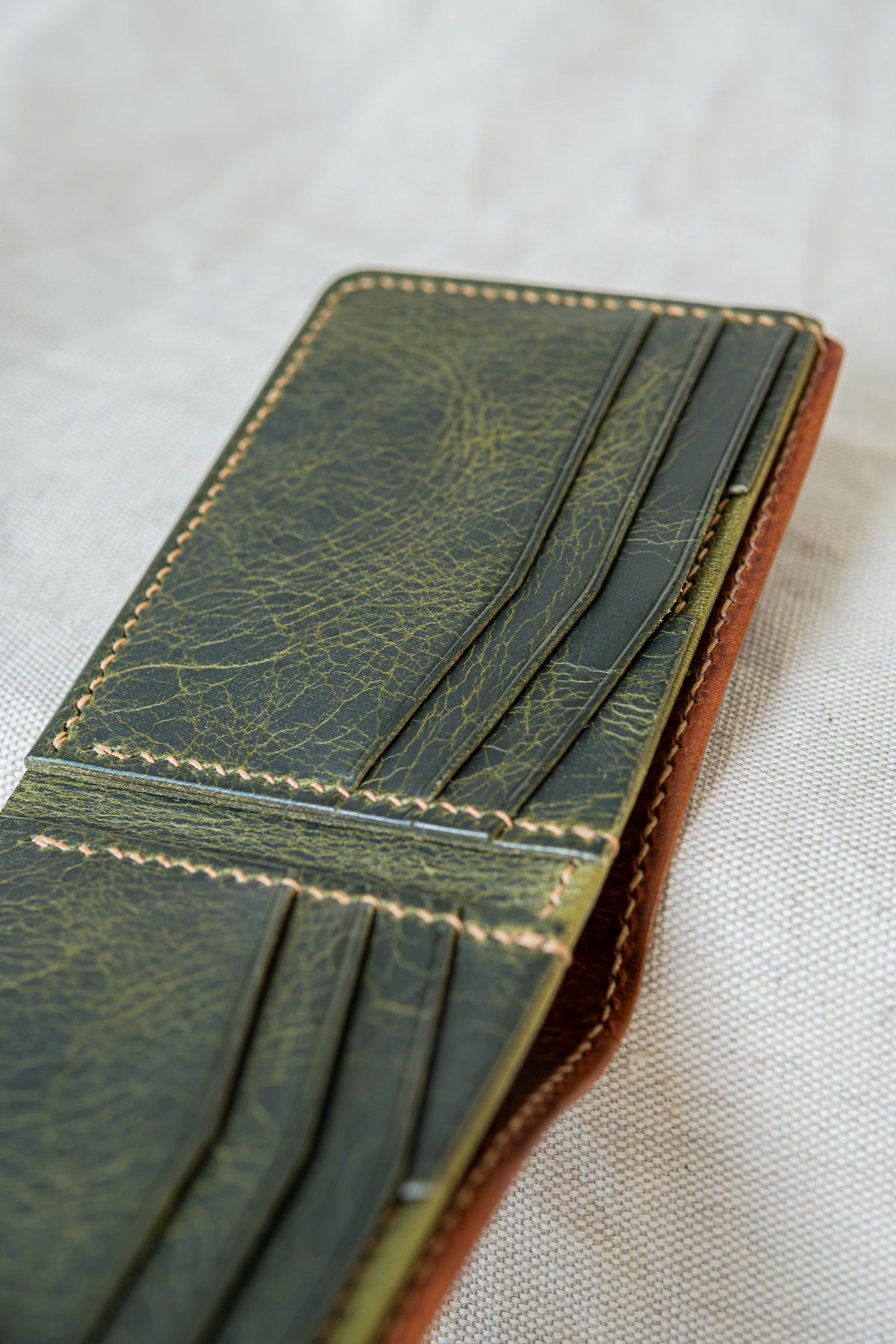Portefeuille Tourmalet en cuir cognac et olive, ouvert avec détails sur les poches
