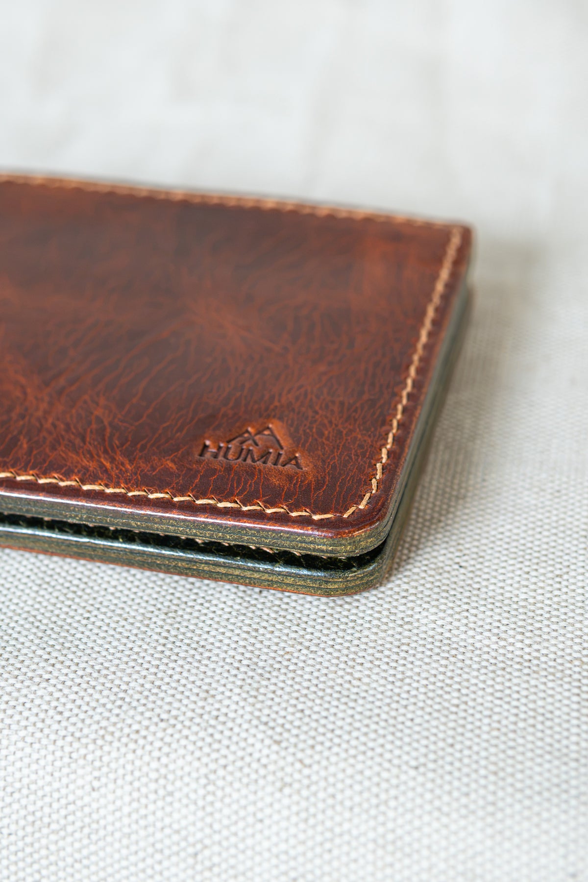 Portefeuille Tourmalet en cuir cognac et olive, détail logo et couture main au point sellier