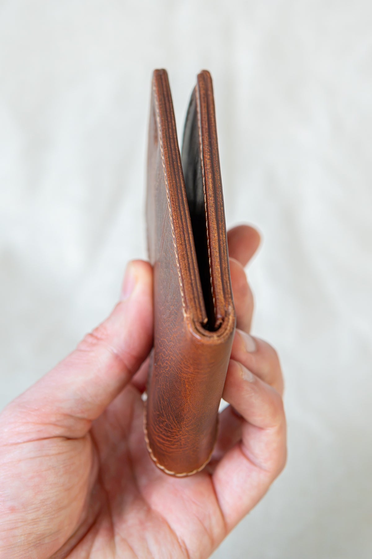 Portefeuille Vignemale en cuir cognac, tenu en main fermé