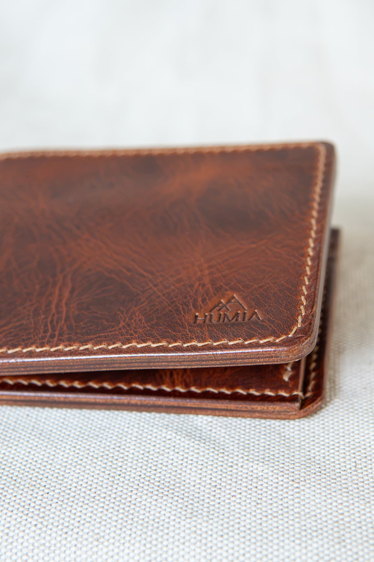 Portefeuille Vignemale en cuir cognac, détail sur le logo et la couture main