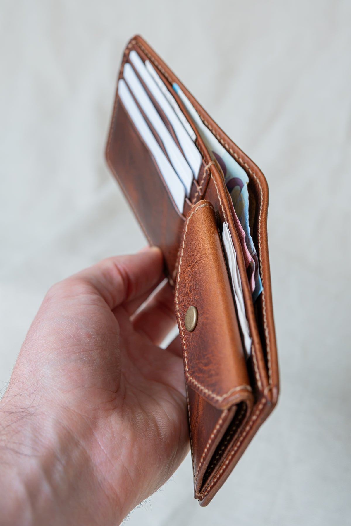 Portefeuille Vignemale en cuir cognac, tenu en main avec cartes et billets
