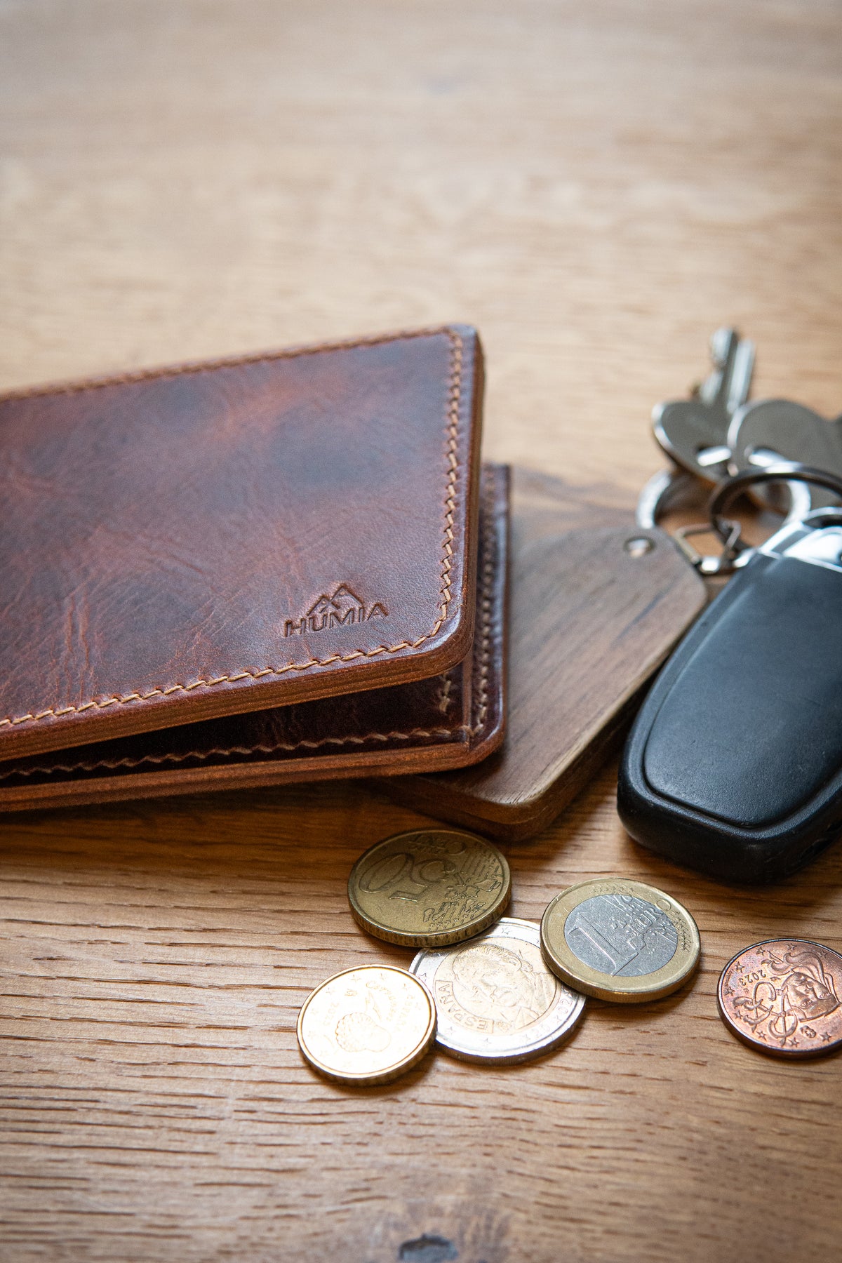 Portefeuille Vignemale en cuir cognac, posé sur table bois avec clés et pièces monnaie