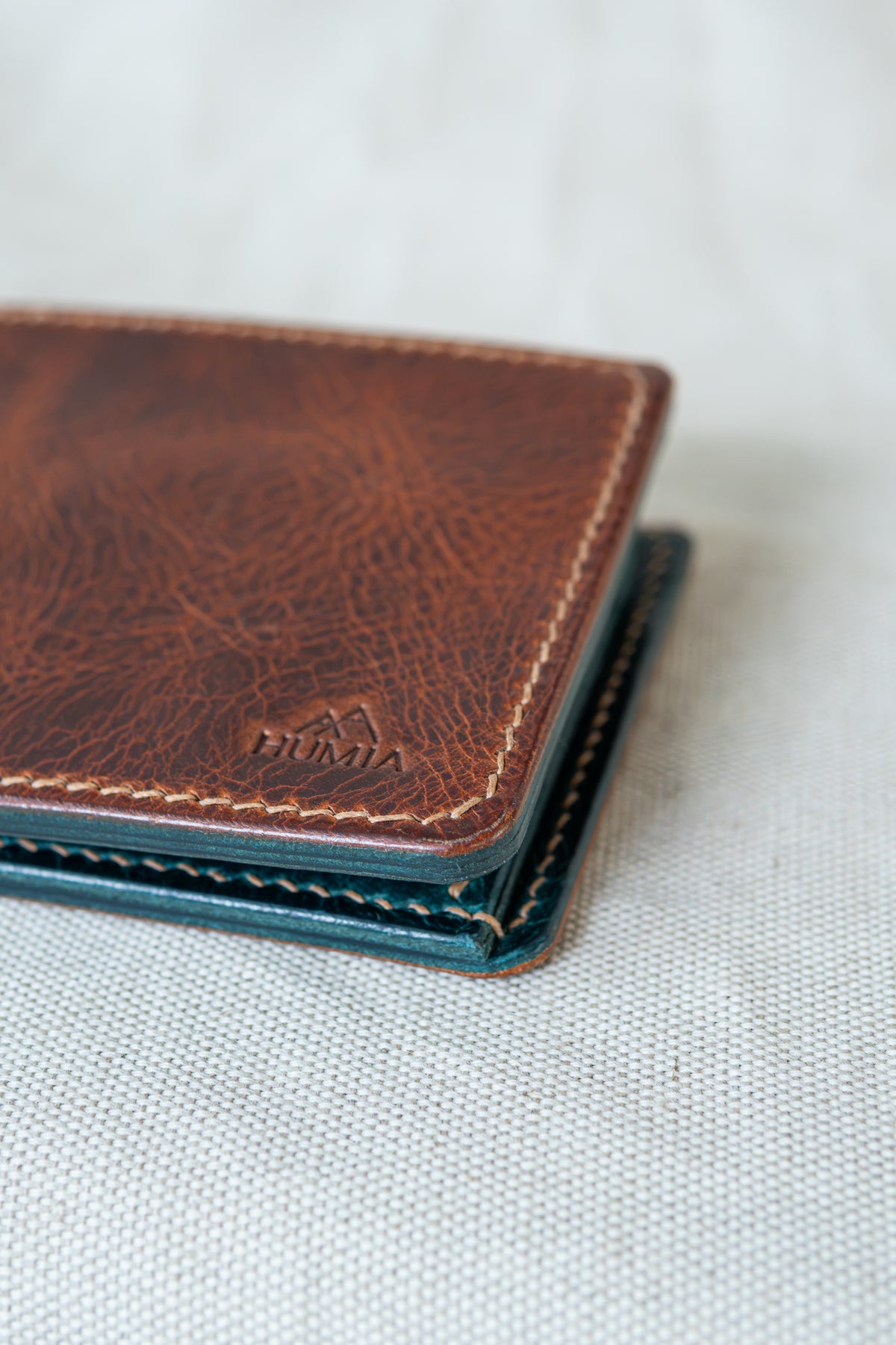 Portefeuille Vignemale en cuir cognac et turquoise, détail sur logo et couture main