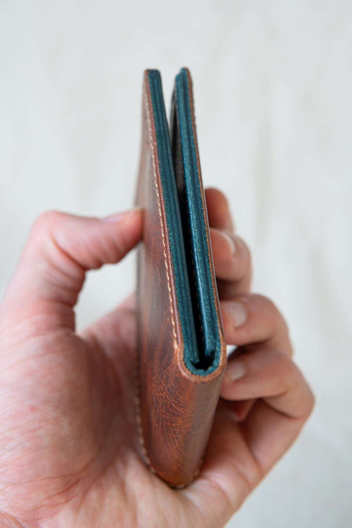 Portefeuille Vignemale en cuir cognac et turquoise, tenu en main fermé